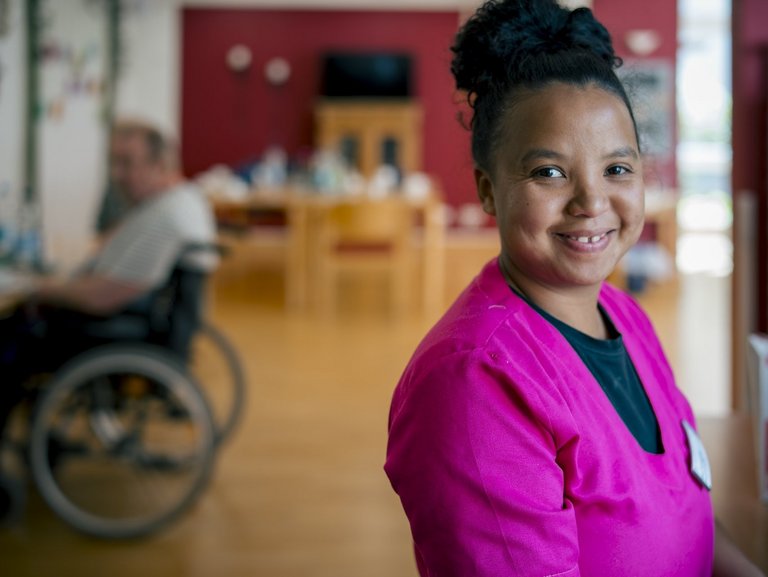 Eine Mitarbeiterin des Hauses lächelt in die Kamera.