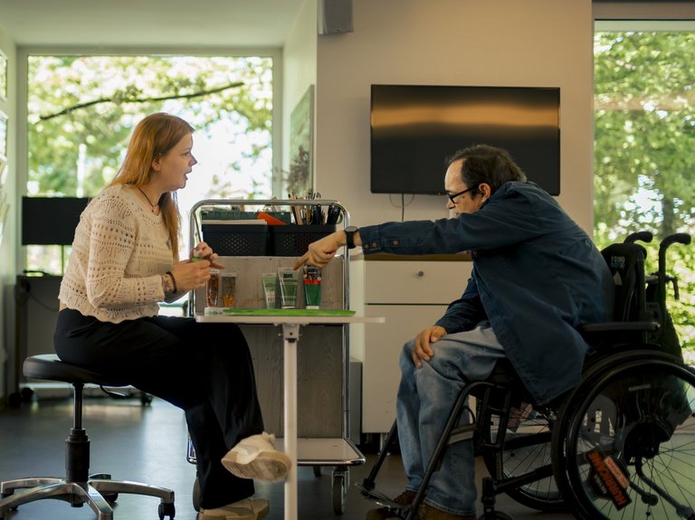 Eine Mitarbeiterin und ein Bewohner arbeiten gemeinsam an einem Kreativprojekt.